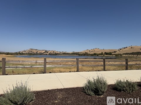 A view of a lake with a fence and some greenery in the foreground.