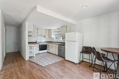 A kitchen with white appliances and brown chairs.