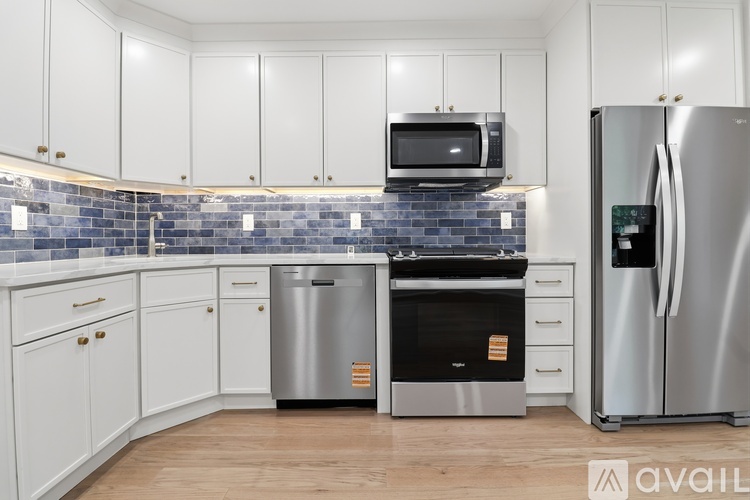 A kitchen with white cabinets and a blue tile backsplash.