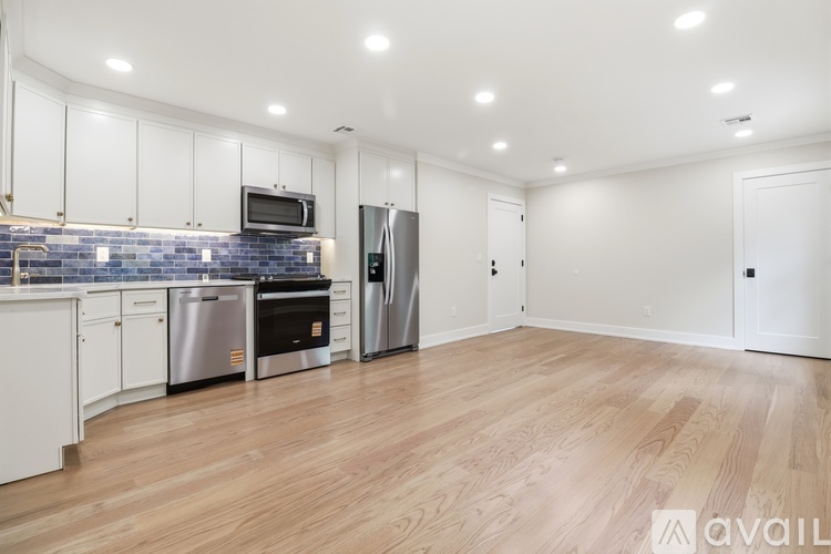 A kitchen with white cabinets and a wooden floor.