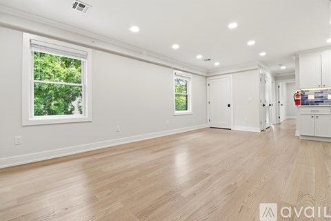 A spacious room with wooden flooring and white walls.