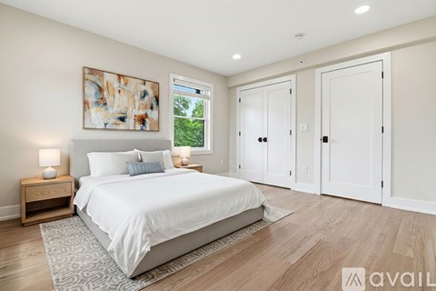 A bedroom with a large bed, two nightstands, and a painting on the wall.