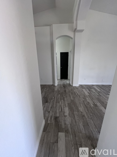 A hallway with a wooden floor and white walls.