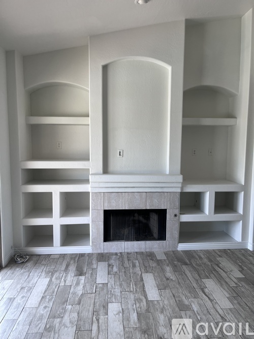 A living room with a fireplace and built-in shelves.