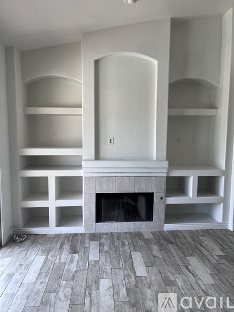 A living room with a fireplace and built-in shelves.