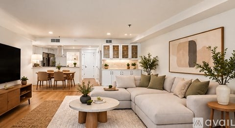 A modern living room with a large couch, a coffee table, and a flat-screen TV.