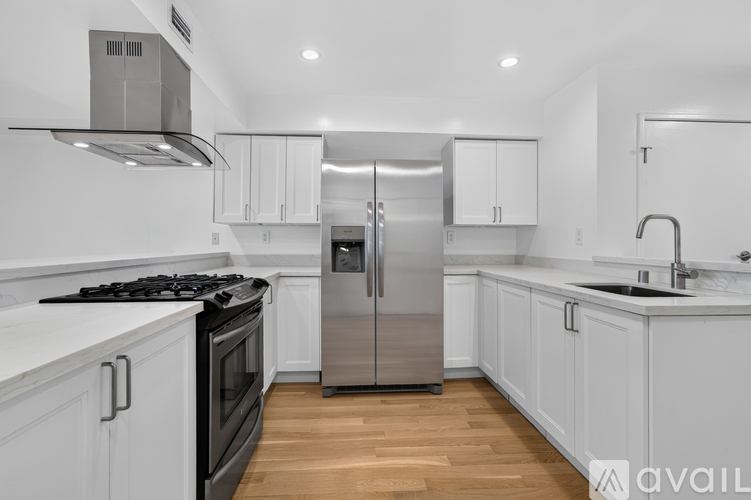A modern kitchen with white cabinets and a stainless steel refrigerator.