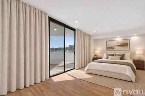A bedroom with a large bed and a view of the outside through a glass door.