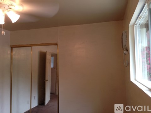 A room with a ceiling fan and a window with a view of a building outside.