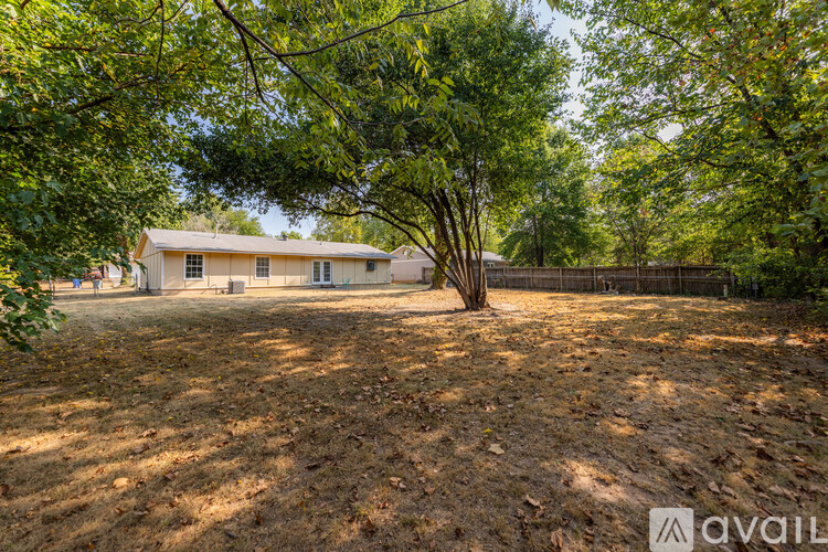 A house is surrounded by trees and has a fence in front of it.