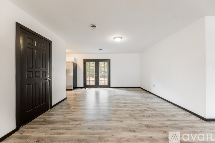 A spacious room with wooden flooring and a large black door.