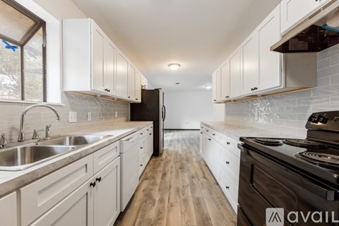 A kitchen with white cabinets and a black refrigerator.