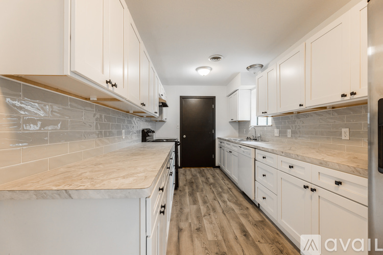 A kitchen with white cabinets and a black door.