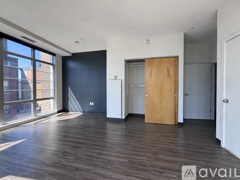 A spacious room with wooden floors and a large window.