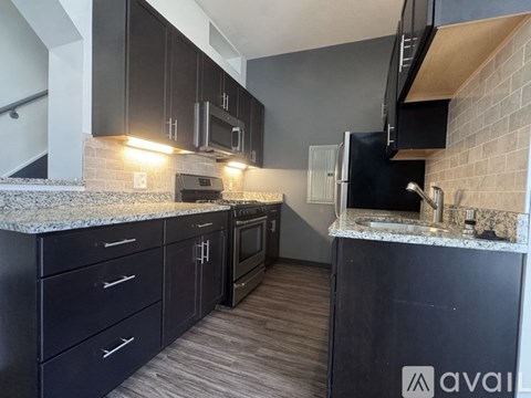 A kitchen with black cabinets and a granite countertop.