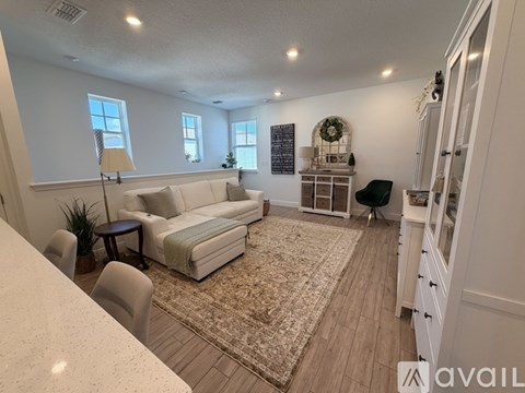 A living room with a white couch, a chair, and a rug.