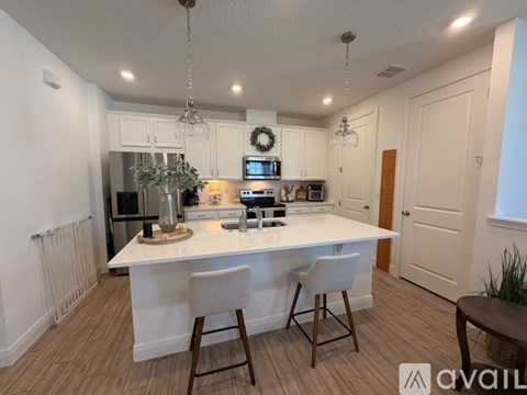 A kitchen with white cabinets and a white island with a wreath on top.