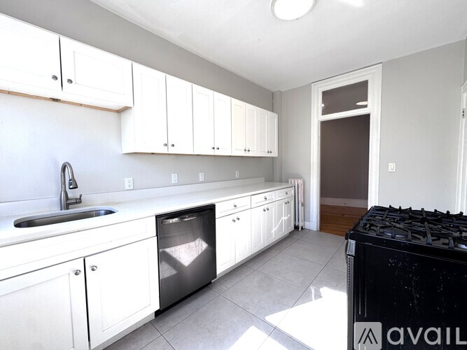 A kitchen with white cabinets and a black stove top.
