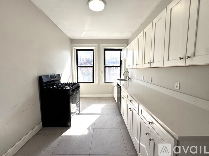A kitchen with white cabinets and a black stove top oven.