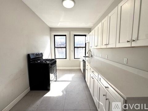 A kitchen with white cabinets and a black stove top oven.