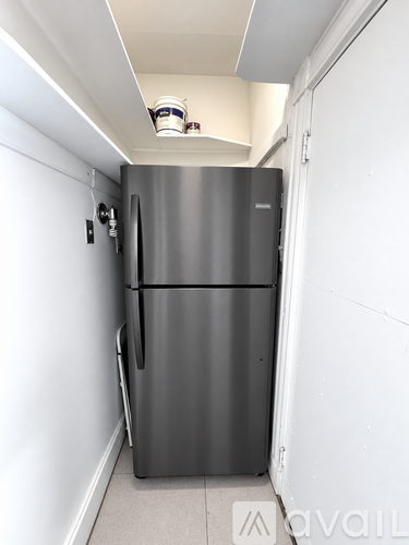 A stainless steel refrigerator in a narrow hallway.