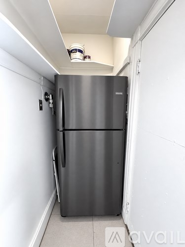A stainless steel refrigerator in a narrow hallway.