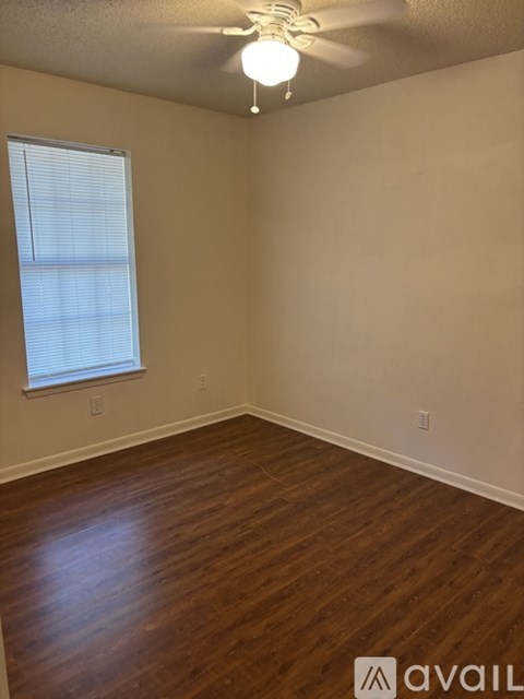 A room with wooden flooring and a ceiling fan with a light.