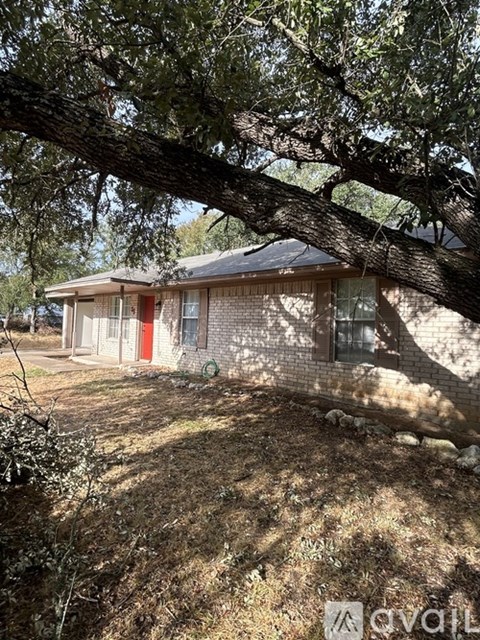 A house with a red door is surrounded by trees.