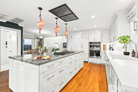 A modern kitchen with white cabinets and a wooden floor.