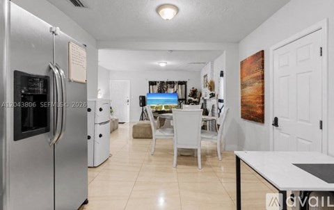 A kitchen with a refrigerator, table and chairs.