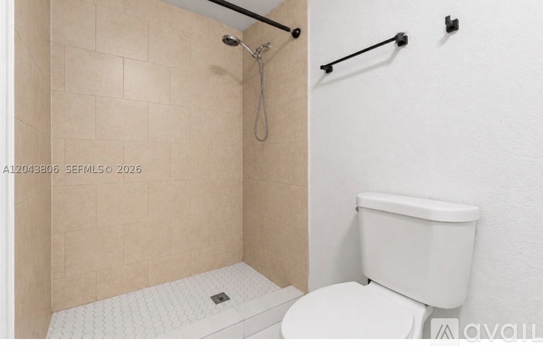 A white toilet in a bathroom with a tiled shower area.