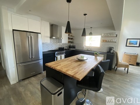 A kitchen with a wooden table and black chairs.