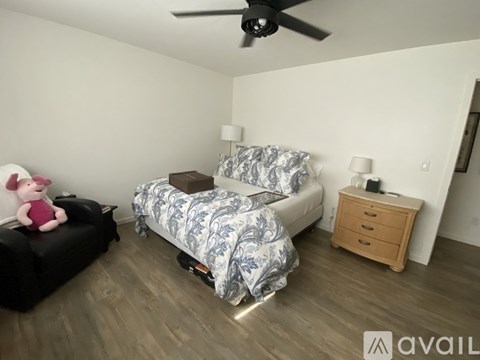 A bedroom with a bed, nightstand, and a ceiling fan.