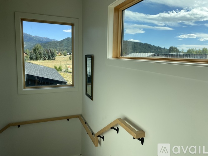A room with a window overlooking a field and trees.