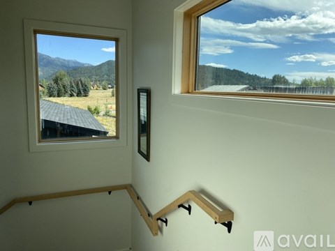 A room with a window overlooking a field and trees.
