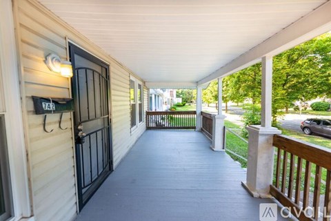 A porch with a black gate and a white wall.