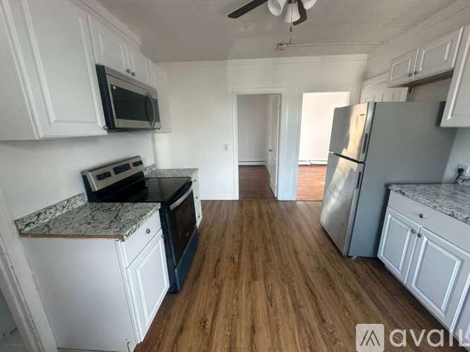 A kitchen with white cabinets and a wooden floor.