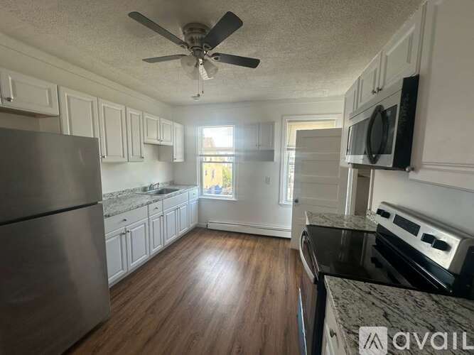 A kitchen with a stainless steel refrigerator and wooden floors.
