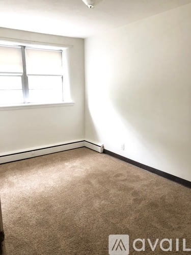 A carpeted room with a window and Avail logo.