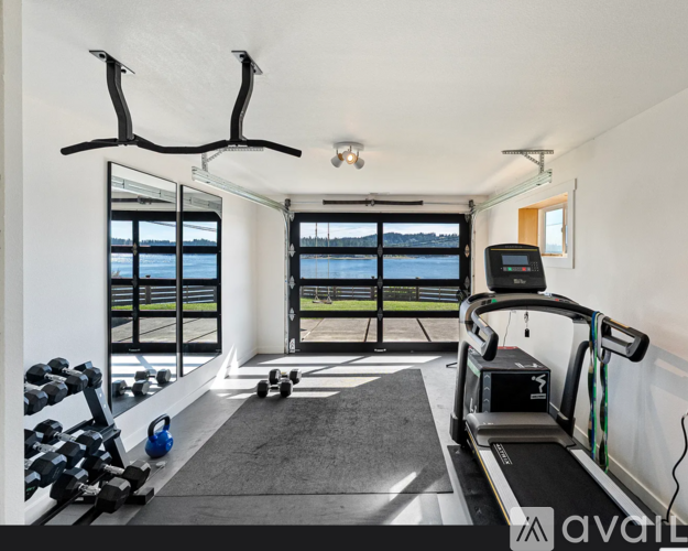 A well-equipped home gym with a treadmill, dumbbells, and a mirror.