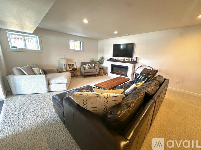 A living room with a black leather couch and a fireplace.