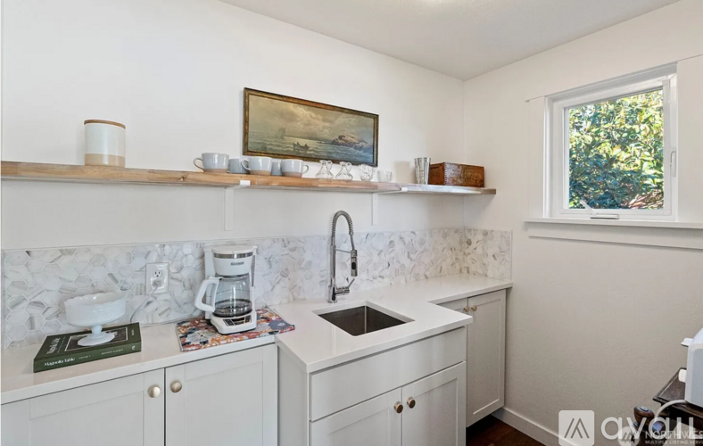 A kitchen with white cabinets and a marble backsplash.
