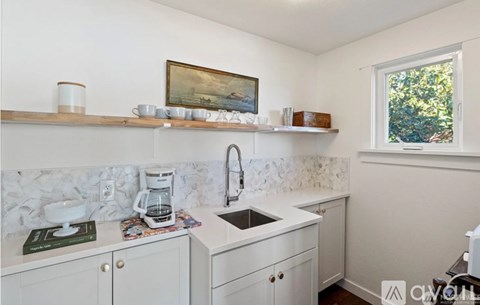 A kitchen with white cabinets and a marble backsplash.