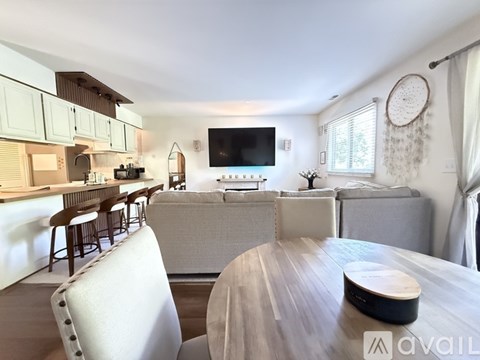 A modern living room with a grey sofa and a wooden dining table.