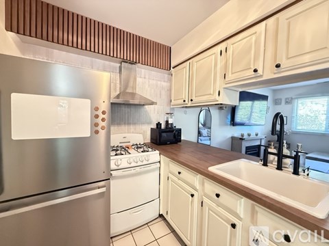 A kitchen with a stainless steel refrigerator and white cabinets.