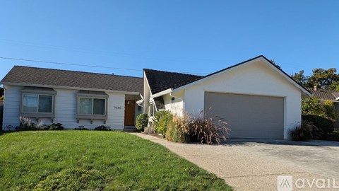 A white house with a brown roof and a garage door.