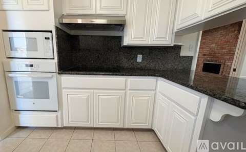 A kitchen with white cabinets and a black countertop.