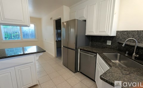 A kitchen with a black countertop and white cabinets.