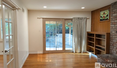 A room with a wooden floor and a glass door leading outside.