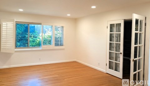 A room with a white door and a window with white blinds.